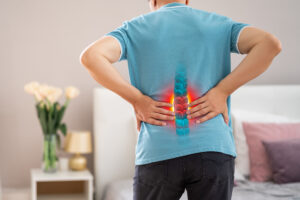 Person clutching lower back after spinal injury has left them in pain.