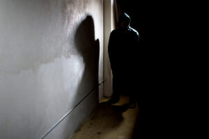 A criminal walks down a dark alley.