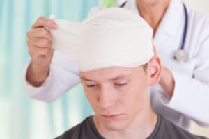 Young man having his head bandaged after an assault in the workplace.