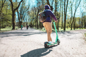 Man riding e scooter through public park.