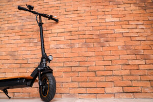 Black scooter parked against brick wall.